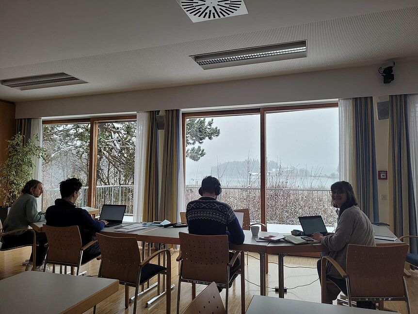 Seminar room with lake view. Four persons working on tables on their computers with view to the lake. 